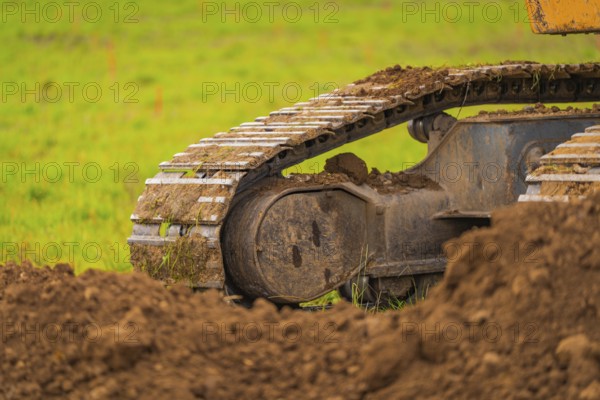 Detailed view of the chains of an excavator covered with soil, on a construction site, Energiewende, construction of PV open space, Baden-Württemberg, Germany