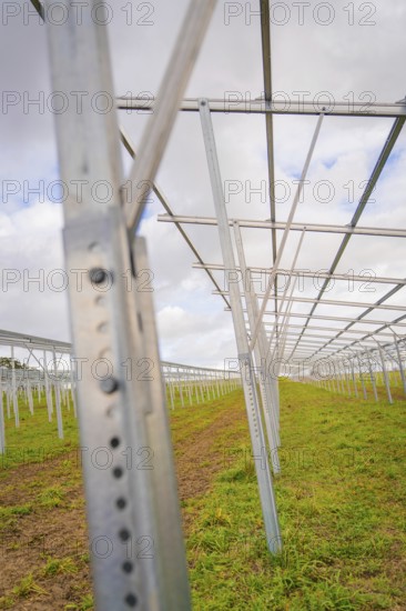 Empty metal structures for solar systems on a green field under cloudy sky, Energiewende, construction of PV open space, Baden-Württemberg, Germany