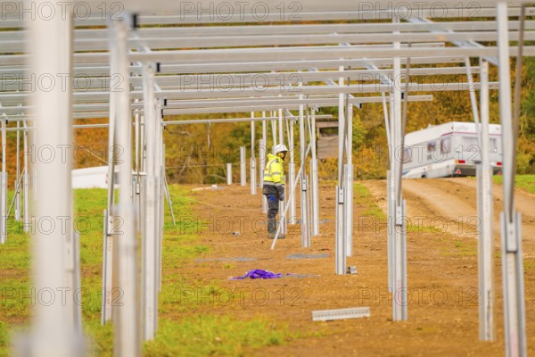Workers with motorhome in the background working on the construction of solar panels in a field, Energiewende, construction of PV open space, Baden-Württemberg, Germany
