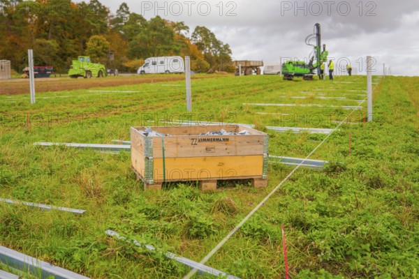 A wooden box in a meadow with building elements, surrounded by green grass and autumn landscape, Energiewende, construction of PV open space, Baden-Württemberg, Germany