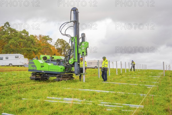 A drilling rig is operated by workers on a green field in autumn, Energiewende, construction of PV open space, Baden-Württemberg, Germany
