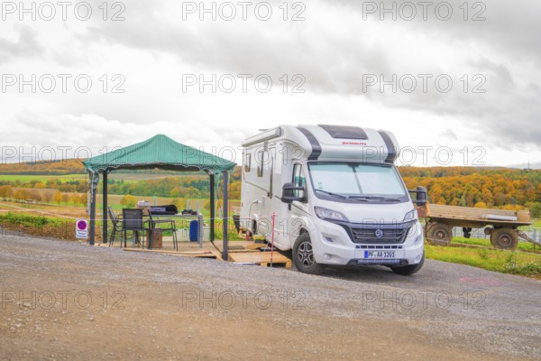 A motorhome with a small pavilion on a hill in front of an autumn landscape, Energiewende, construction of PV open space, Baden-Württemberg, Germany