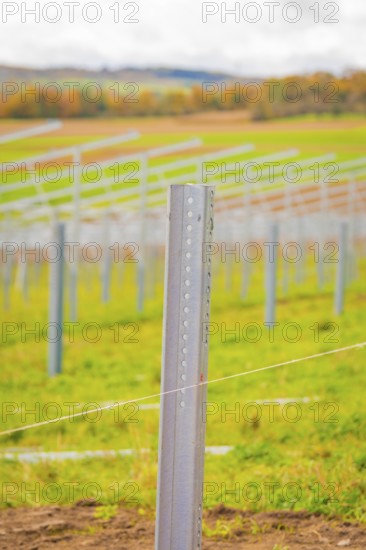 Close-up of a metal rod that is part of a larger field installation, with blurred landscape in the background, energy transition, construction of PV open space, Baden-Württemberg, Germany