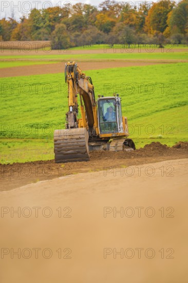Excavator works on a hill in a green field in autumn, energy revolution, construction of PV open space, Baden-Württemberg, Germany