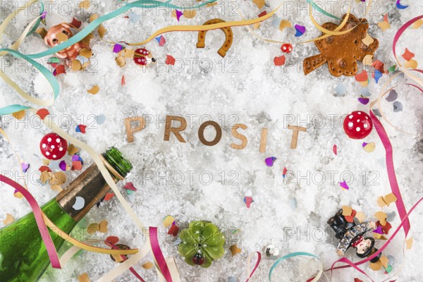 Cheers in the snow surrounded by lucky charms and champagne bottle, New Year's Eve