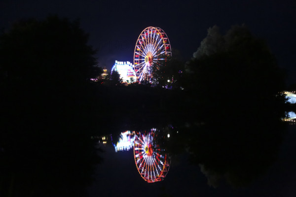 Fairground in Ulm Friedrichsau at night, folk festival, hustle and bustle, fair, Ferris wheel, amusement park, amusement attraction, ride, artificial light, darkness, reflection in natural lake, Ausee, Ferris wheel, Ulm, Baden-Württemberg, Germany