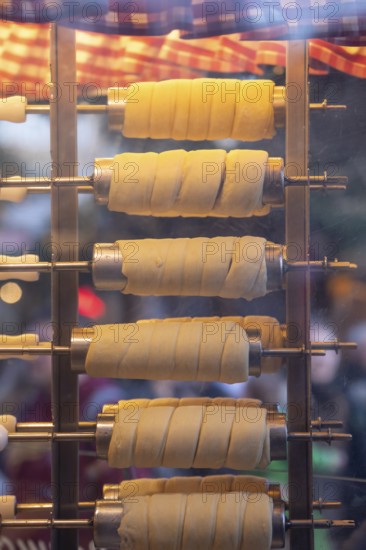 The trendy Chimney Cake stand at Stuttgart Christmas Market offers freshly baked, sweet treats. The aromatic scents attract numerous market visitors who enjoy the unique dessert