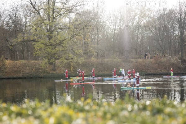 Water sports enthusiasts dressed up as Santa Claus ride SUPs on the Spree am Park at the presidential triangle in Berlin on 30.11.2025