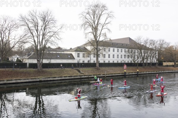 Water sports enthusiasts dressed up as Santa Claus ride SUPs on the Spree in front of Bellevue Palace in Berlin on 30.11.2025