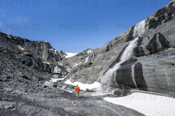 Tourist standing at a glacier stream, glacier ice and waterfall, Worthington Glacier State Recreational Site, Chugach Mountains, Alaska, USA