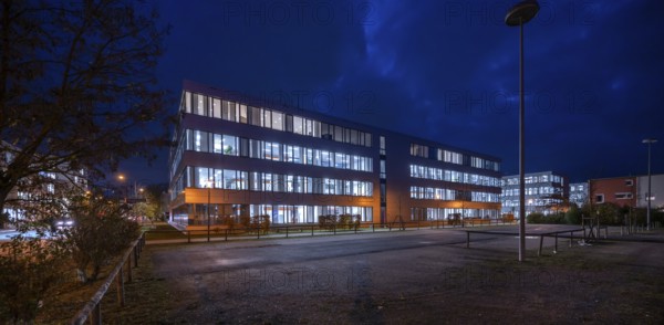 Siemens office buildings illuminated in the evening, empty parking spaces in front, Erlangen, Middle Franconia, Bavaria, Germany