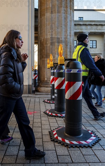 Passers-by at the security barrier made of massive bollards at the Brandenburg Gate passage, Berlin, Germany