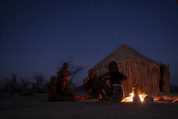Himba at the campfire in the evening, night view, Himba huts, traditional Himba village in the savanna, Kaokoveld, Kunene, Namibia