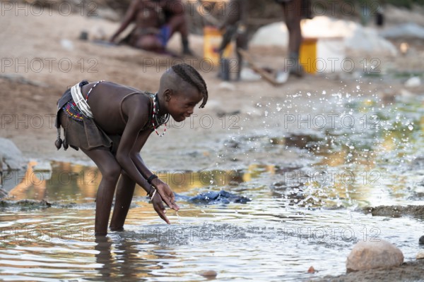 Himba child washing with water on a river, traditional Himba, Kaokoveld, Kunene, Namibia