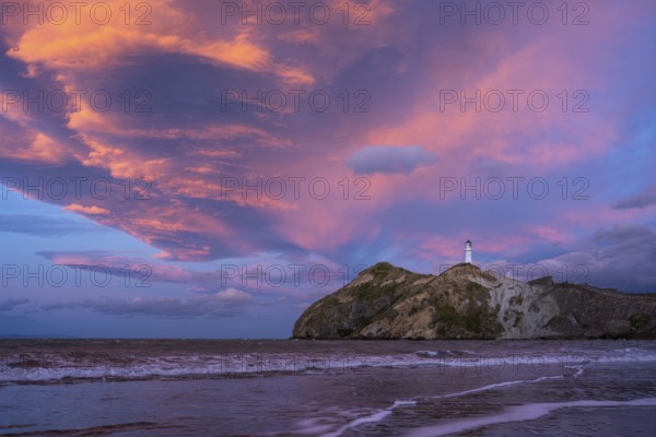 Castlepoint Beach, ocean and lighthouse on a rock, evening, sunset, dramatic sky. Castlepoint, Wairarapa Coast, Wellington Region, North Island, New Zealand