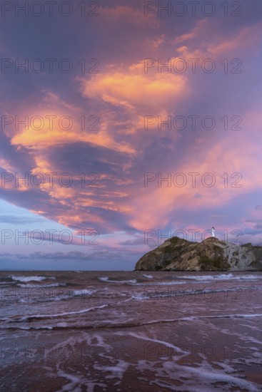 Castlepoint Beach, ocean and lighthouse on a rock, evening, sunset, dramatic sky. Castlepoint, Wairarapa Coast, Wellington Region, North Island, New Zealand