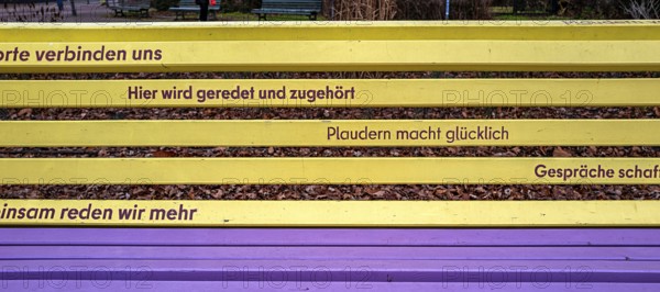 Park bench with slogan for talking and chatting in yellow and purple, Berlin, Germany