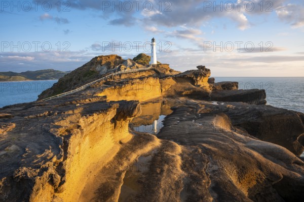 Castlepoint lighthouse on a rock, sea, sunrise. Castlepoint, Wairarapa Coast, Wellington Region, North Island, New Zealand