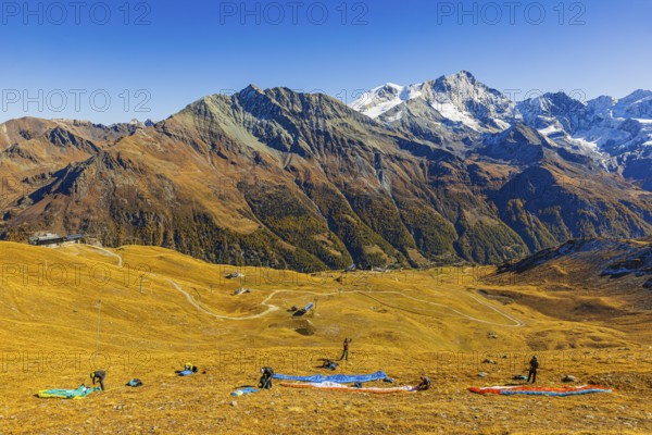Paragliders prepare their start, summit of the Corne de Sorebois, with the backdrop of the Valais Alps behind, Val d'Anniviers, Canton of Valais, Switzerland
