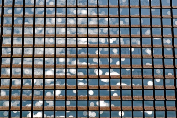 Rusty grid in front of a reflecting water surface, North Rhine-Westphalia, Germany