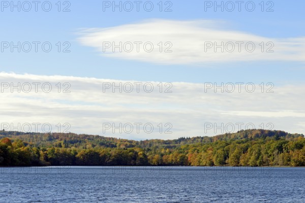 View over Lake Möhnesee, mixed autumn forest on the shore, blue sky, Möhnetalsperre, North Rhine-Westphalia, Germany