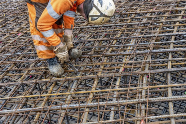 Assembly of reinforcing steel for the reinforced concrete foundation of a wind turbine, a mesh of rebar and reinforcing steel mesh, connecting the steel elements with binding wire, twisting with tongs, over 100 tons of reinforcing steel were used, the wind turbine will have a hub height of 160 meters, part of a new wind farm in Sauerland, near Balve, North Rhine-Westphalia, Germany