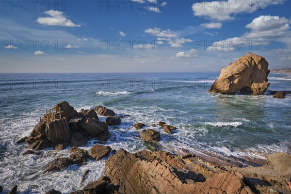 Penedo do Guincho, a large boulder rock arch at Praia da Santa Cruz, Portugal, with ocean waves and sandy beach