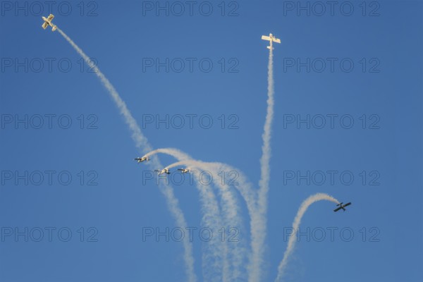 Stunt aerobatic planes performing stunts in blue sky with smoke trail. Concept of teamwork, collaboration, coordination, trust, precision, difficulty, challenge, speed, synergy