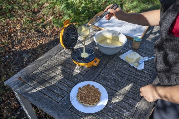 Preparation of waffles with a waffle iron on an outdoor garden table, Othenstorf, Mecklenburg-Western Pomerania, Germany