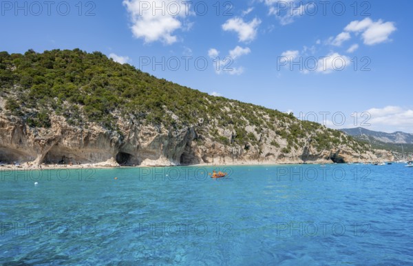 Kayakers in clear blue water, picturesque rocky coast, cliffs and Cala Luna beach, Golfo di Orosei, Baunei, Sardinia, Italy