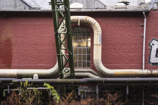 District heating pipeline in front of old industrial buildings on the banks of the Wupper, Wuppertal, Germany