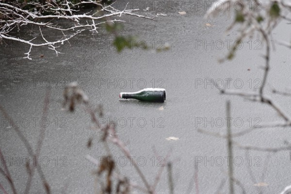 Symbolic picture of garbage in nature, bottle on frozen lake, winter, Germany