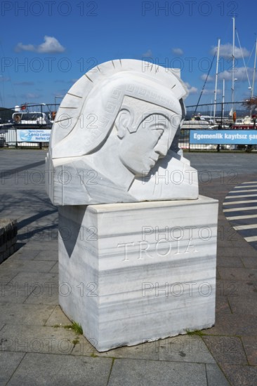 A marble sculpture with the inscription 'Troia' on the harbor, boats in the background, Çanakkale, Canakkale, Marmara region, Turkey