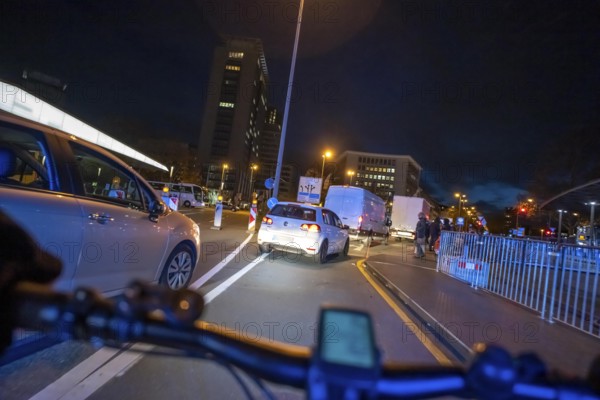 Cycling in the city, in the dark, in the evening, cycling on a bike lane, marked, between 2 lanes, Huyssenallee, in downtown Essen, North Rhine-Westphalia, Germany