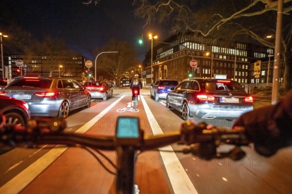 Cycling in the city, in the dark, in the evening, cycling on a bike lane, marked in red, Huyssenallee, in downtown Essen, North Rhine-Westphalia, Germany