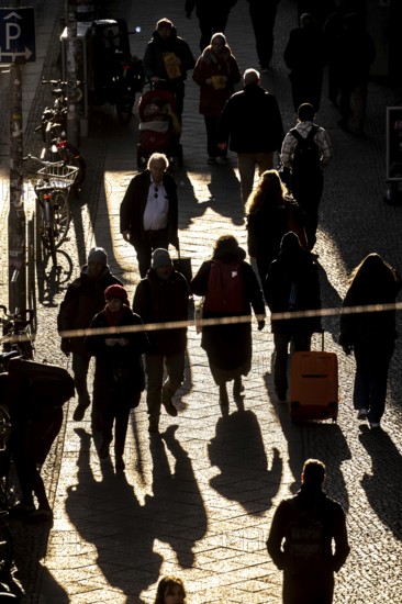 Passers-by on a Friedrichstraße sidewalk in Berlin, shade, low sun, winter, Germany