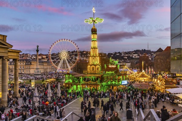 Sunset at Stuttgart's Christmas market in the Schlossplatz area. With around 3.5 million visitors, it is one of the largest and most beautiful in all of Germany. Christmas pyramid and Ferris wheel in front of the New Castle. Stuttgart, Baden-Württemberg, Germany