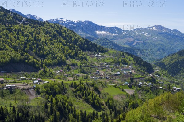 A small town is nestled in a green mountain landscape under clear skies, village in the Lesser Caucasus on the way to the Goderdzi Pass, Ajara region, Adjara, autonomous republic, Georgia
