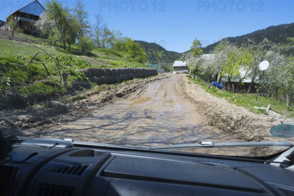 A muddy country road is viewed from a driving perspective through a car window, campers on a four-wheel drive track on the way to the Goderdzi Pass, Ajara region, Adjara, Autonomous Republic, Georgia