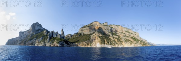 Panorama, picturesque rocky coast, cliffs with caves in the morning light, L'Aguglia rock peak, blue sea and Cala Goloritzé beach, Golfo di Orosei, Baunei, Sardinia, Italy