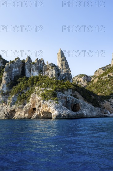 Picturesque rocky coast, cliffs with caves in the morning light, L'Aguglia rock peak, blue sea and Cala Goloritzé beach, Golfo di Orosei, Baunei, Sardinia, Italy