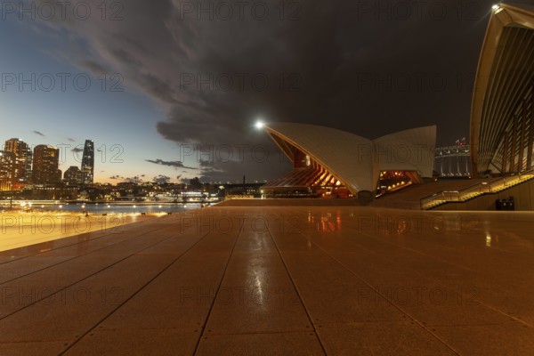 Cloudy sky over skyscrapers and promenade, Sydney CBD at dusk. At the Sydney Opera House, Australia