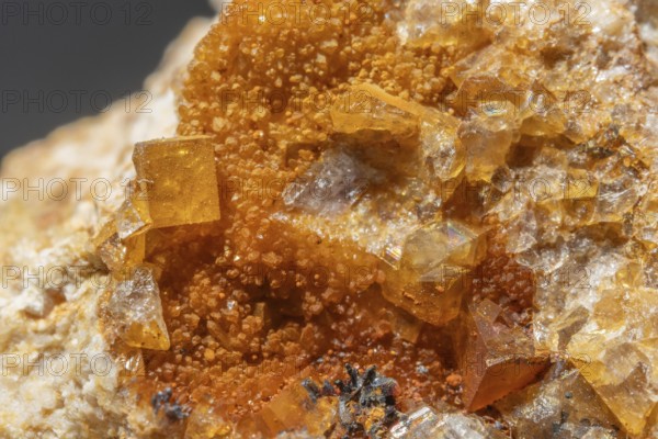 Shiny crystals of blue and orange color can be seen in this mineral formation. They are sparkling and show interesting textures in a natural setting