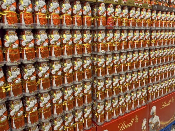Display on the shelf of chocolate Santa Claus chocolate Santa Claus Santa Claus Santa Claus Santa Claus chocolate Santa Claus chocolate Santa Claus chocolate lice Santa Claus chocolate lice Santa Claus in color red of red staniol paper made of chocolate arranged like army of Santa Claus, Germany