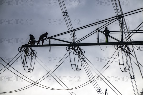 Work on a 380 kV high-voltage overhead line, new construction, along the A57 motorway, near Meerbusch, workers on the boom of the high-voltage pylon, North Rhine-Westphalia, Germany