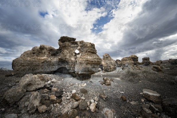 Eroded rock formations in volcanic landscape with dramatic cloudy skies, Ciudad Estratificada or Los Roferos, Antigua Rofera de Teseguite, Lanzarote, Canary Islands, Spain