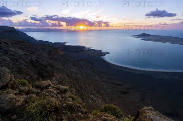 View from steep cliffs to sea and coast with sun stars, Mirador del Porrito viewpoint at sunset, Lanzarote, Canary Islands, Spain