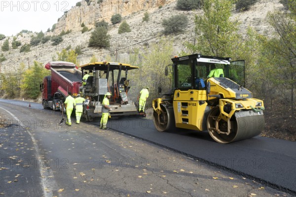 Asphalt road construction team of workers resurfacing tarmac in rural area, near Albarracin, Teruel province, Aragon, Spain