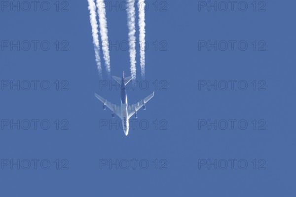Boeing 747 jumbo jet cargo aircraft of Atlas air airlines flying in a blue sky with contrails or vapour trails behind, England, United Kingdom