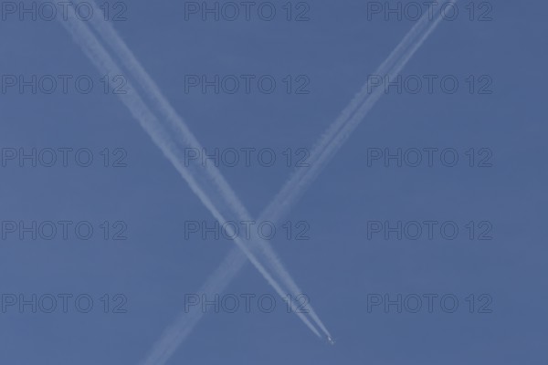 Aircraft contrails or vapour trails crossing in a blue sky, England, United Kingdom